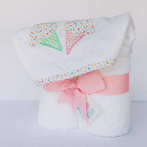 A white hooded towel with a terry lined hood that features an ice cream cone applique, embellished with colorful dots and a pink ribbon.