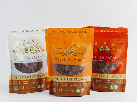 Three packages of Althea Farms pecans on a white background