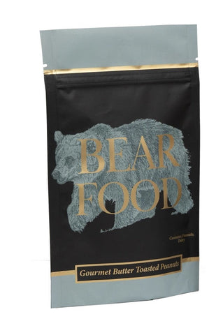 A stand-up pouch of Bear Food Gourmet Butter Toasted Peanuts next to a canister of the same product, both featuring a black and slate blue design with gold lettering and a bear graphic, on a white background.