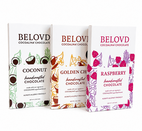 Three Belovd Cocolina Chocolate bars in their retail packaging, displayed side-by-side against a plain white background. The packages are for Coconut, Golden Chocolate, and Raspberry flavors, featuring white boxes with colorful illustrations and text.