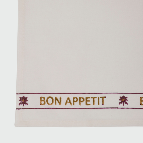 White towel with 'Bon Appetit' text and floral designs on a white background