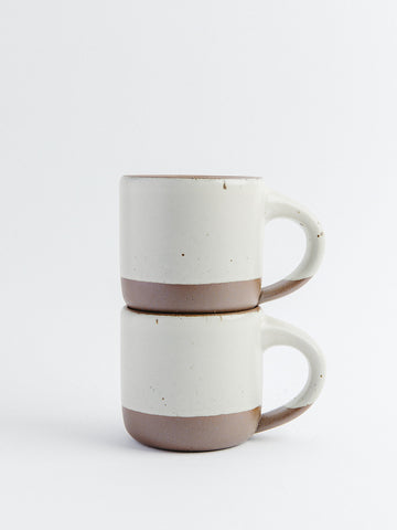Two ceramic mugs stacked on a white background