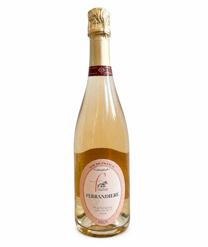 A bottle of Ferrandiere Method sparkling wine, showing the pale pinkish-amber liquid inside a classic champagne bottle with a gold foil top and a pink and white label.