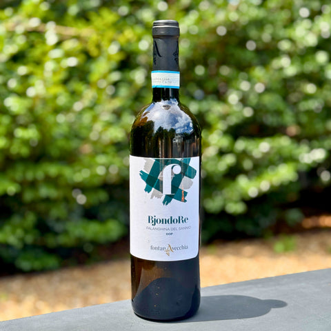 Wine bottle with a label on a surface with greenery in the background