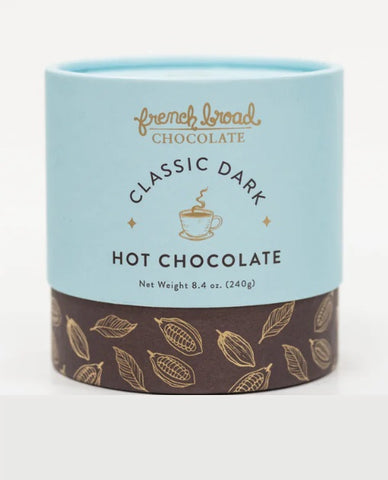 A cylindrical container of French Broad Chocolate Classic Dark Hot Chocolate, featuring a light blue upper section with gold and black lettering, and a dark brown lower section decorated with gold cocoa pod illustrations.