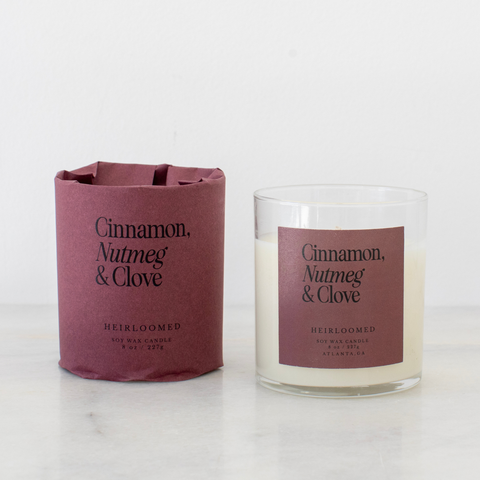 Candle with a purple label and matching packaging on a white background