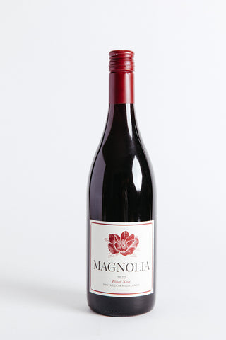 A bottle of Magnolia Santa Lucia Highlands Pinot Noir with a red label and a magnolia flower illustration.