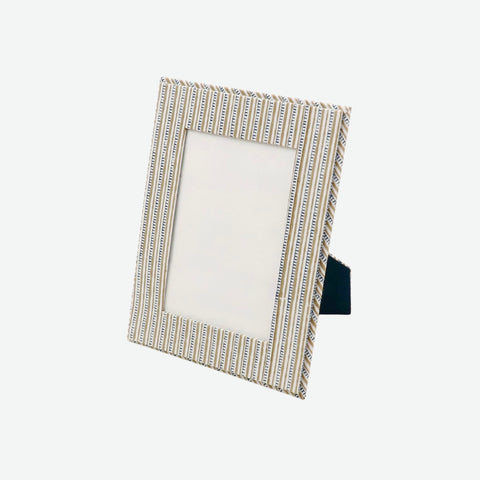 A rectangular picture frame with a textured, vertically striped metallic border in a champagne-gold and silver tone, shown standing at an angle on a plain light gray background.