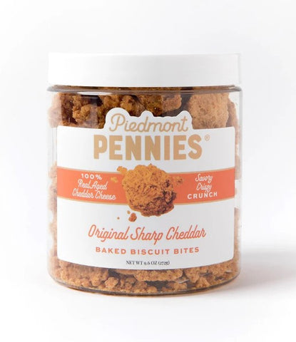 A jar of Piedmont Pennies Original Sharp Cheddar Baked Biscuit Bites on a clean white background. The clear plastic jar shows the brown biscuit bites inside, with a white lid and a white label featuring orange and brown text.
