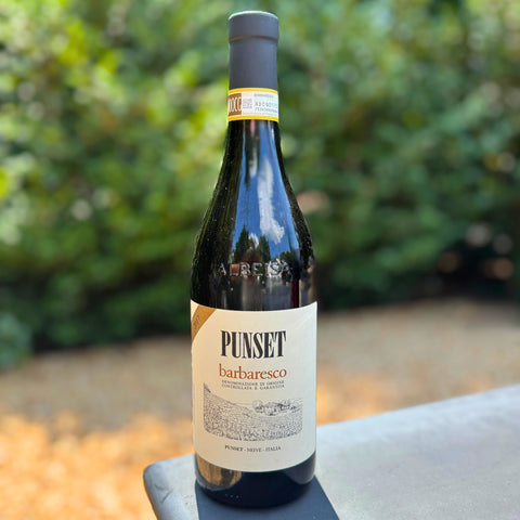 Wine bottle labeled 'Punset Barbaresco' with a blurred green background