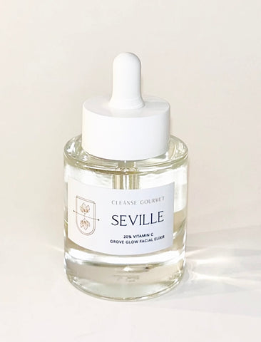A glass dropper bottle of Seville Cleanse Gourmet facial elixir on a light beige background. The bottle is clear glass with a white dropper cap and a white label featuring the brand name 'SEVILLE'.