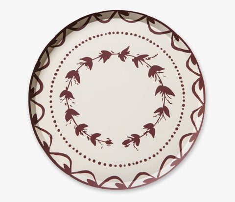 A round ceramic plate with a cream-colored center and a dark brown pattern featuring a leafy wreath, dotted line, and scalloped border.