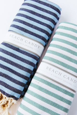 Two striped beach towels, one with blue and white stripes, and the other with green and white stripes, laid out flat.